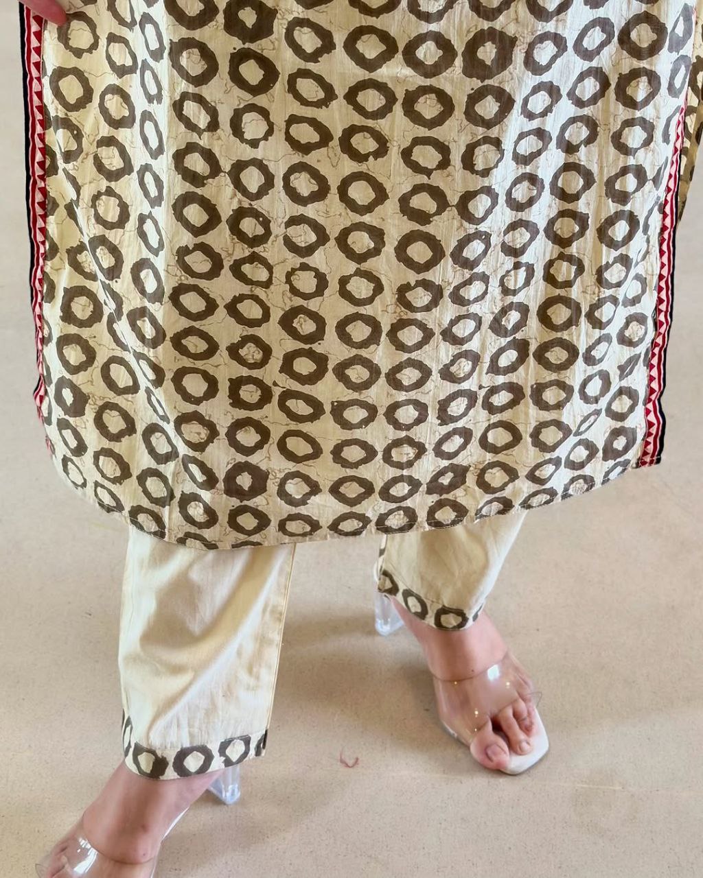 Elevate your ethnic wardrobe with this elegant beige kurti set featuring intricate Ajrakh embroidery on the yoke and sleeves. Paired with matching straight pants and a rich red dupatta, it offers timeless grace for festive and casual wear alike