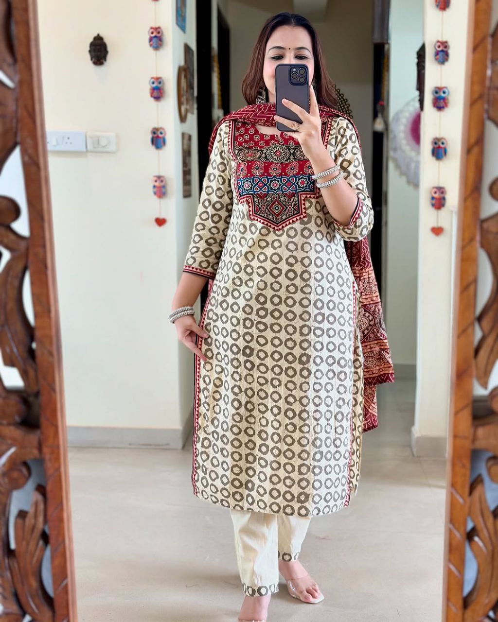 Elevate your ethnic wardrobe with this elegant beige kurti set featuring intricate Ajrakh embroidery on the yoke and sleeves. Paired with matching straight pants and a rich red dupatta, it offers timeless grace for festive and casual wear alike