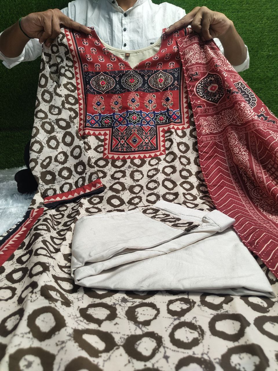 Elevate your ethnic wardrobe with this elegant beige kurti set featuring intricate Ajrakh embroidery on the yoke and sleeves. Paired with matching straight pants and a rich red dupatta, it offers timeless grace for festive and casual wear alike