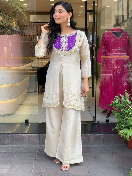 Elevate your ethnic style with this elegant cream kurti set featuring intricate embroidery and a striking purple yoke. Paired with flared pants, this outfit blends tradition with modern flair—perfect for festive occasions or graceful daywear.