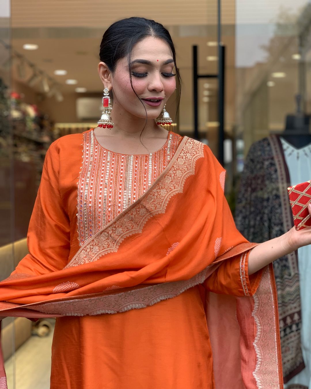 This vibrant orange kurti set exudes elegance with intricate embroidery and a luxurious dupatta featuring delicate border detailing