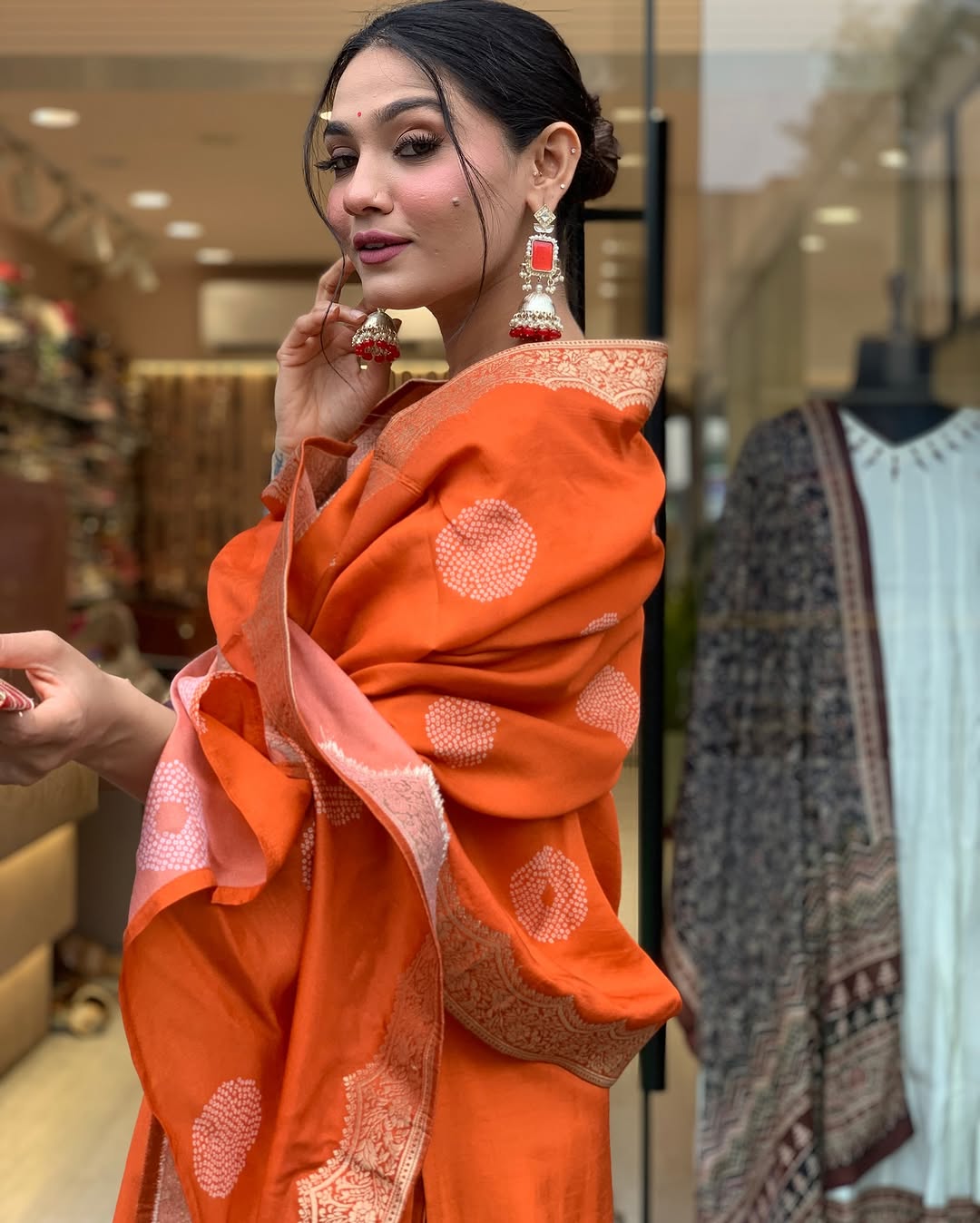 This vibrant orange kurti set exudes elegance with intricate embroidery and a luxurious dupatta featuring delicate border detailing