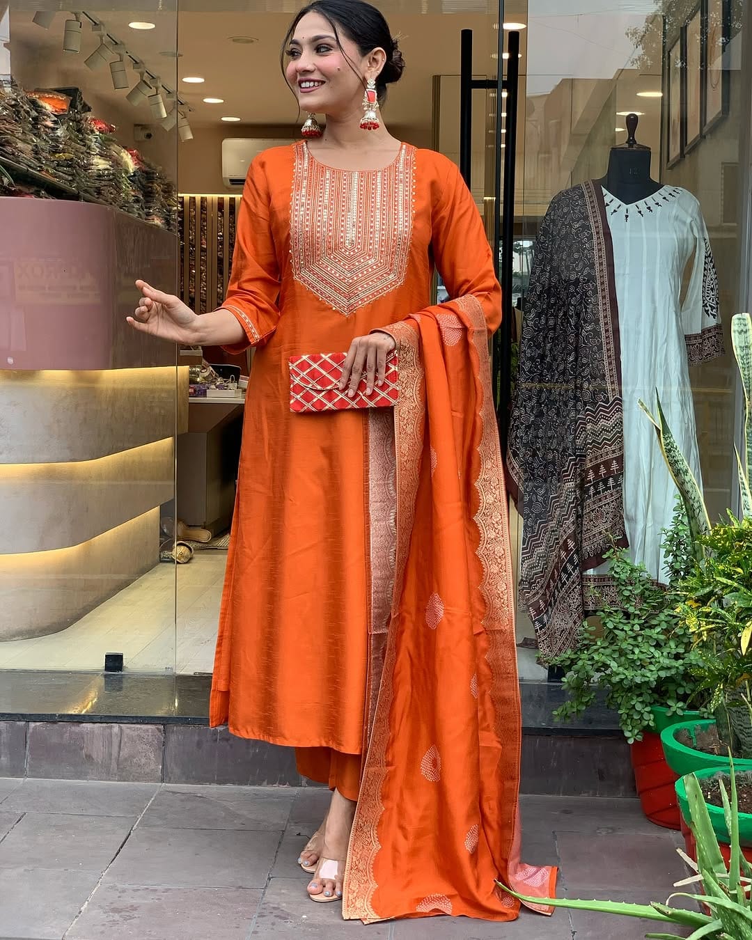 This vibrant orange kurti set exudes elegance with intricate embroidery and a luxurious dupatta featuring delicate border detailing