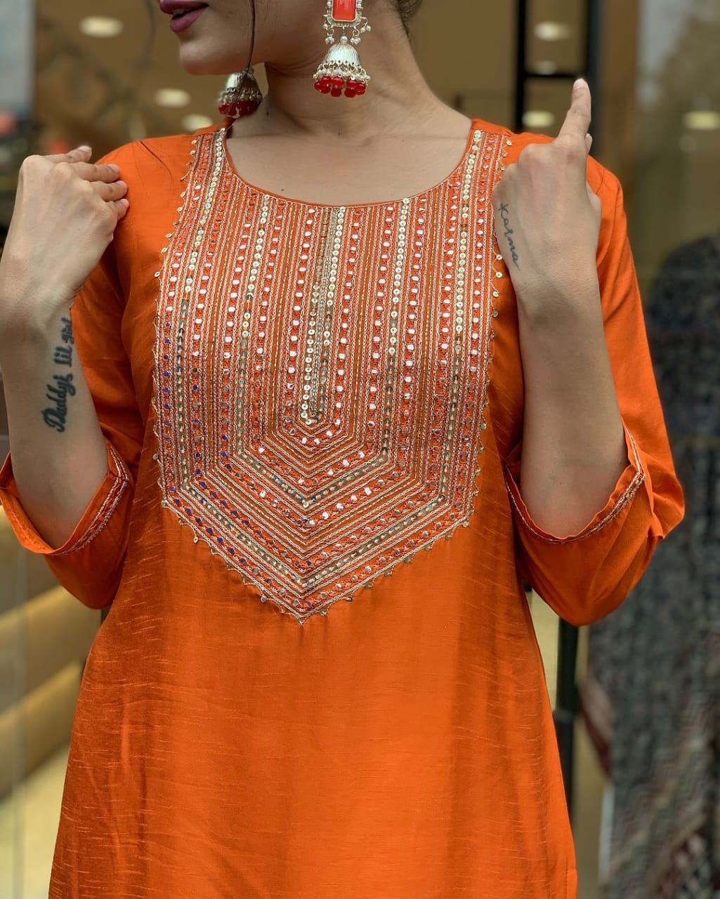 This vibrant orange kurti set exudes elegance with intricate embroidery and a luxurious dupatta featuring delicate border detailing