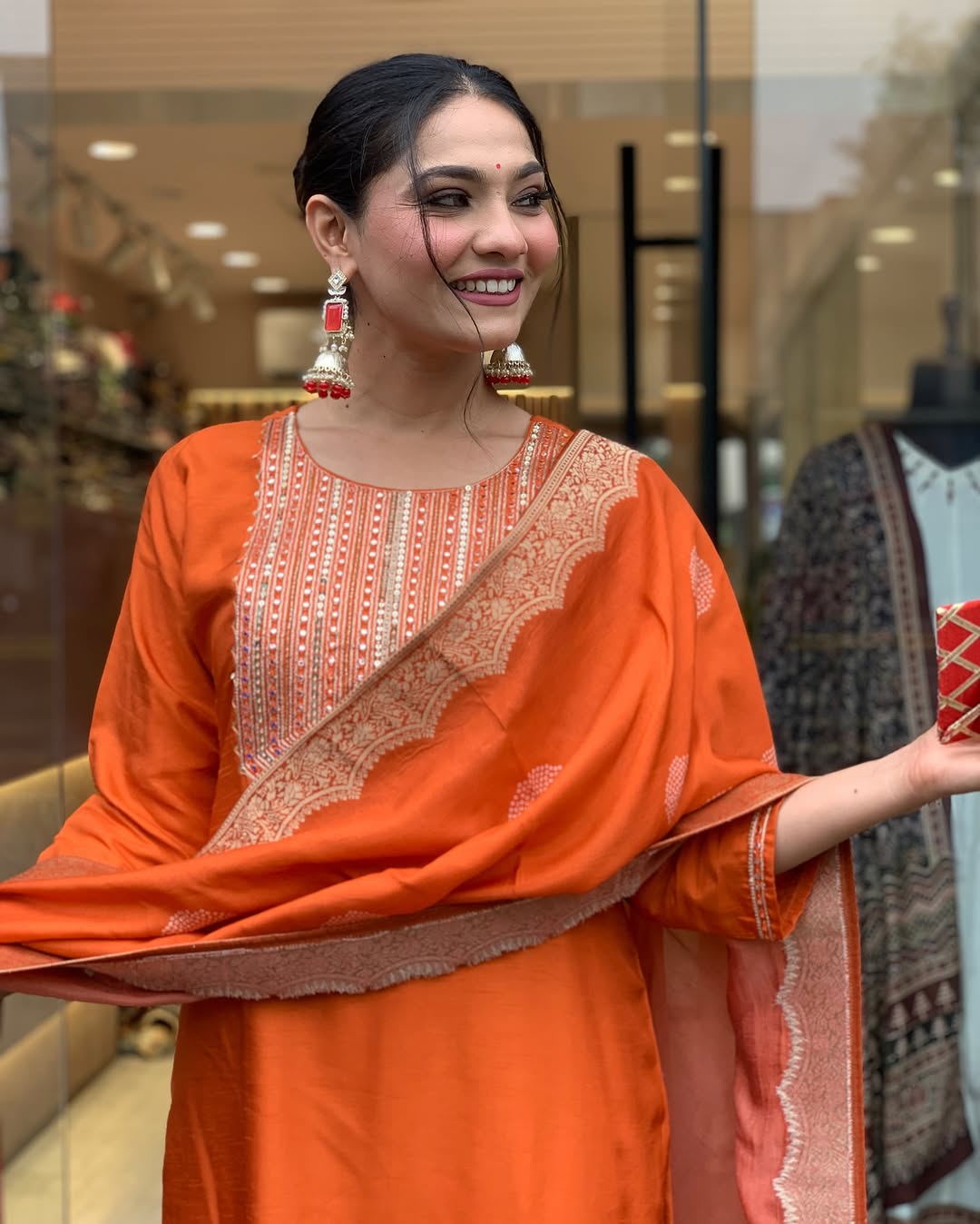 This vibrant orange kurti set exudes elegance with intricate embroidery and a luxurious dupatta featuring delicate border detailing
